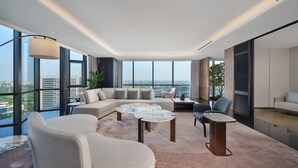 Amplia sala de estar con un sofá modular grande, una mesa redonda de centro y vistas de la ciudad a través de amplios ventanales.