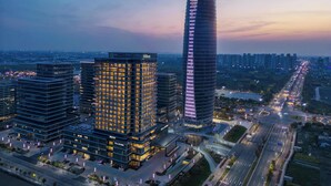 Un moderno complejo hotelero con varias torres altas, una imponente torre curva y una iluminada calle urbana al anochecer.