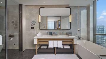 Un baño moderno con un espejo grande, dos lavamanos, una bañera y una cabina de ducha de vidrio.