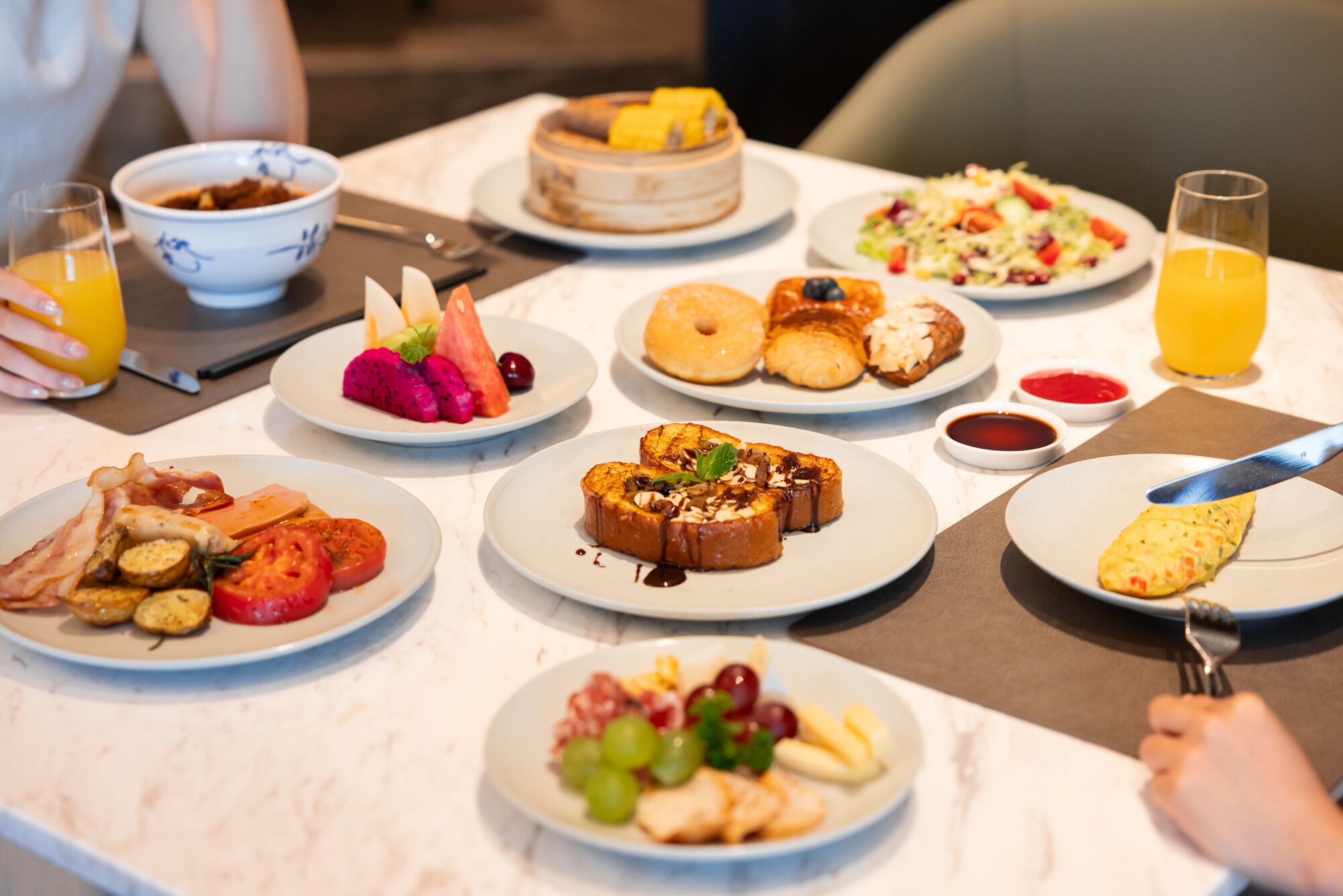 A breakfast buffet with various dishes including eggs, bacon, toast, fruit, and pastries.