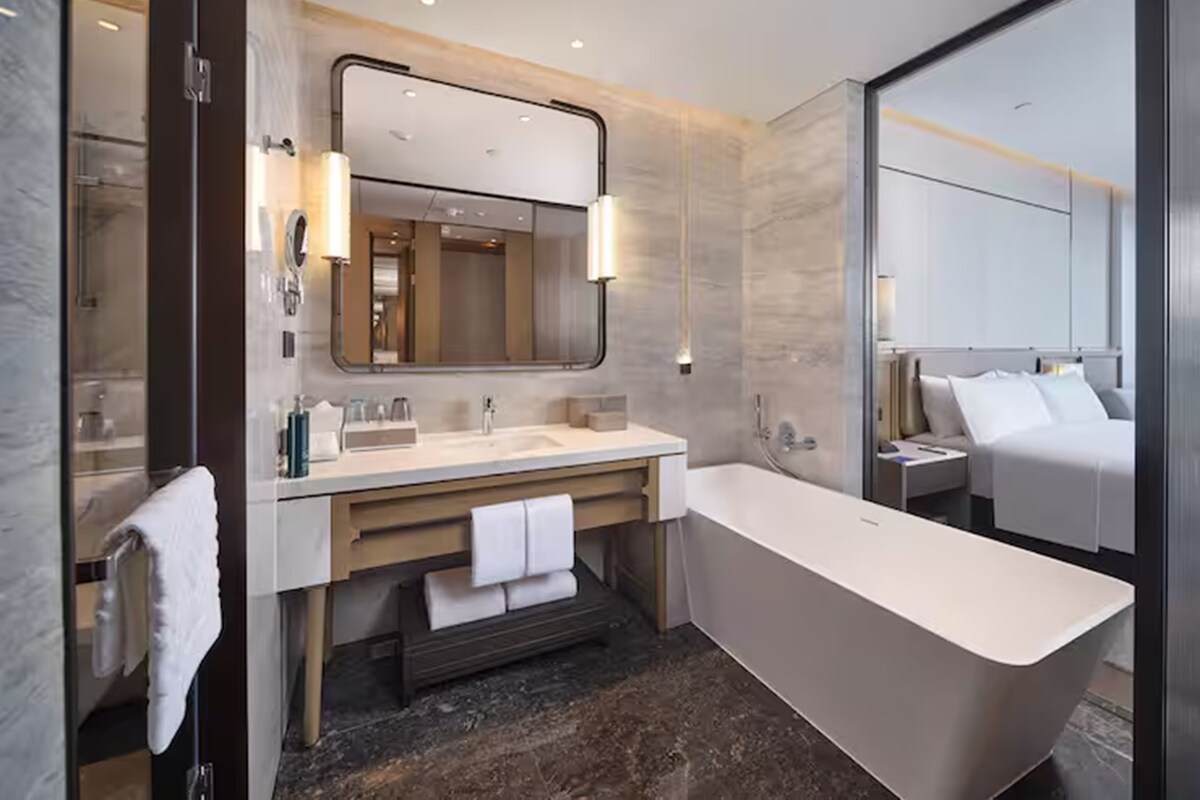 A modern bathroom with a large bathtub, dual sinks, a vanity with a mirror, and a separate shower area.