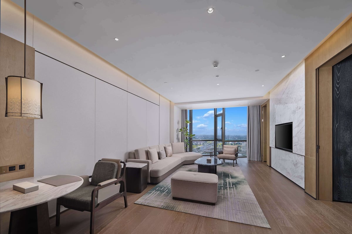 Una sala de estar moderna con un sofá, sillones, una mesa de centro y un televisor montado en la pared.