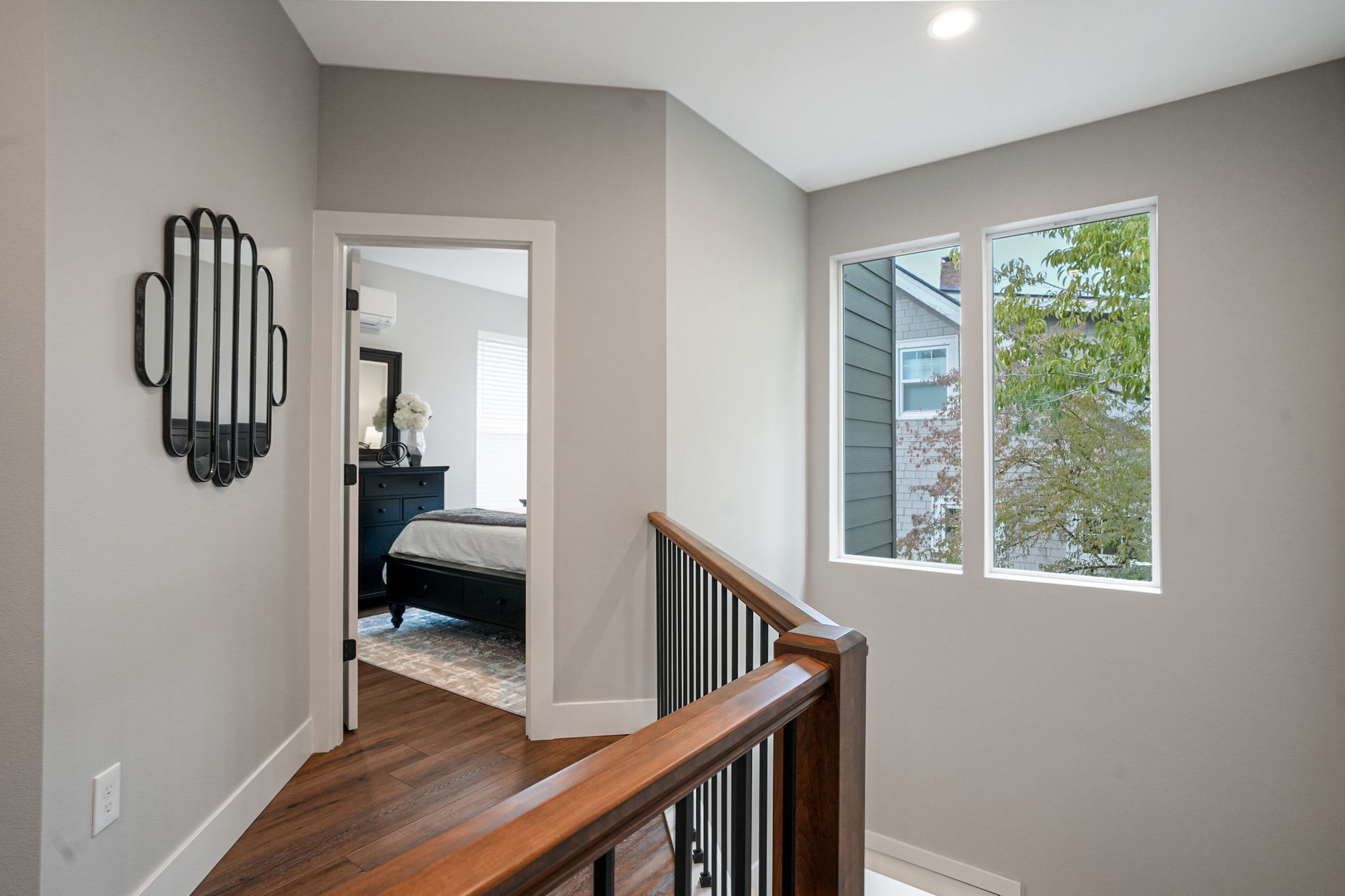 A staircase with a wooden handrail leading to a bedroom with a bed and dresser.