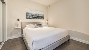 Un dormitorio moderno con una cama grande, lámparas de noche y una obra de arte colgada en la pared.