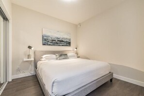 Ein modernes Schlafzimmer mit einem großen Bett, Nachttischlampen und einem Wandbild.