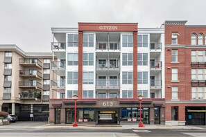 A multi-story building with a prominent 'CITIZEN' sign, featuring a brick facade, multiple balconies, and a ground-level commercial space with a storefront. - King Bed and Coastal Art Decor in Old Town (Victoria Central British Columbia Provincial Government)