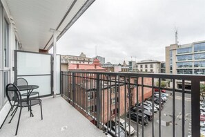 Ein Balkon mit Tisch und Stühlen, mit Blick auf einen Parkplatz und Gebäude.
