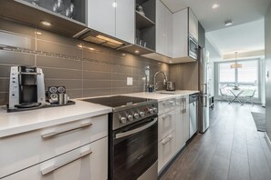 A modern kitchen with a built-in oven, a coffee machine, and a stainless steel refrigerator. - Bright Old Town Suite with City Views (Victoria Central British Columbia Provincial Government)