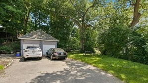 Une maison avec un garage et deux voitures garées devant.