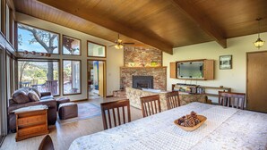 A spacious living area with a fireplace, large windows, and a dining table set with pinecones.