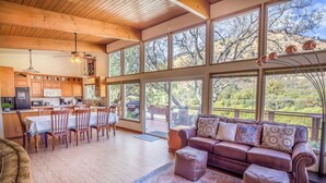 A spacious living area with a large window, a cozy seating area, and a kitchen with wooden cabinets and a dining table.