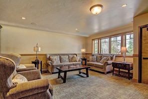 A spacious living room with a large window, two sofas, a coffee table, and two lamps.