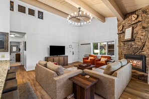 Un salón amplio con chimenea, televisor y una pared de acento de piedra.