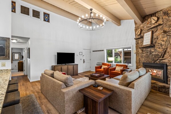 Un salón amplio con chimenea, televisor y una pared de acento de piedra.
