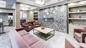 A modern living room with a marble wall, a flat-screen TV, and a coffee table. - Mountain Getaway in Canmore! Sleeps 6 - Pool & Hottub (Canmore)