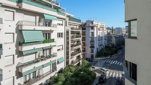 A multi-story residential building with balconies, green awnings, and a clear street view. - Studio Amanda - Welkeys (Nice)