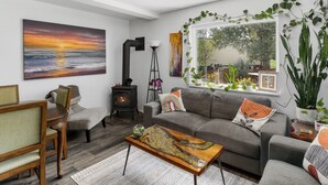 A living room with a sofa, coffee table, and a painting of a sunset. - Beautiful Home on River - 30 Day Rental Discounts! (Steamboat Springs)