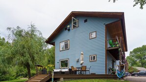 A two-story house with a deck, outdoor furniture, and a hammock. - Beautiful Home on River - 30 Day Rental Discounts! (Steamboat Springs)