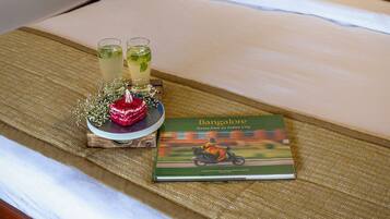 A neatly made bed with a book titled 'Bangalore' and two glasses of a beverage on the bedspread.