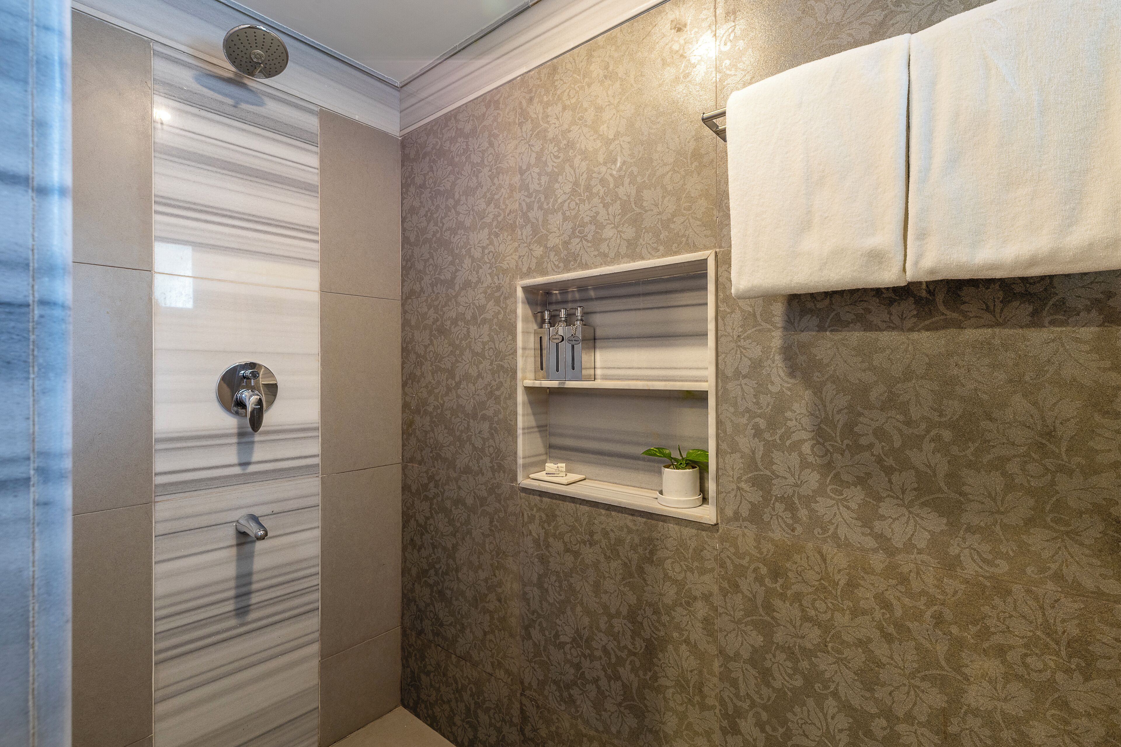 Ein Badezimmer mit Dusche, Handtuchhalter und Ablage für Pflegeprodukte.