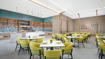 A modern restaurant with yellow chairs, a central island, and a patterned backsplash.