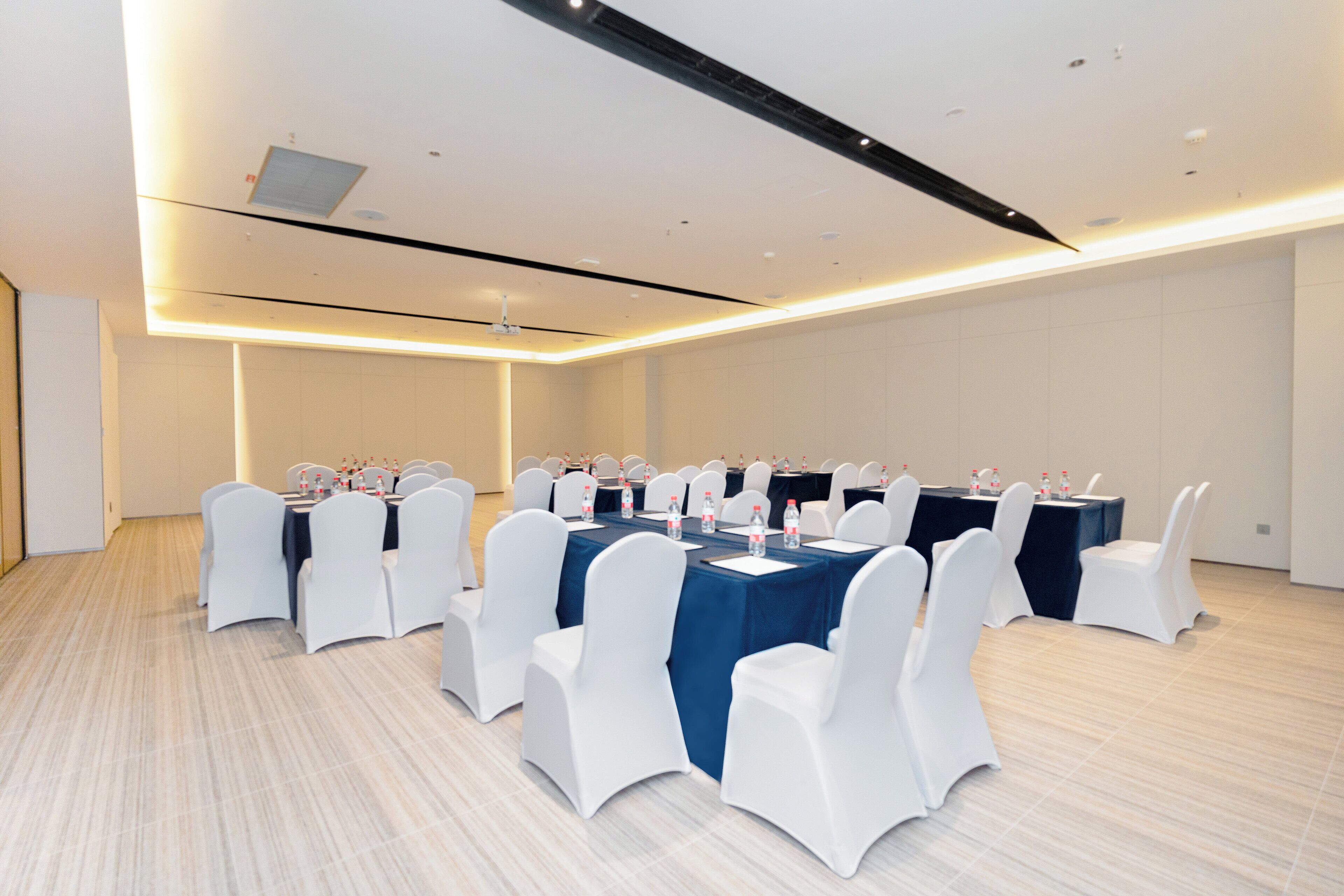 A conference room with round tables, white chairs, and blue tablecloths.