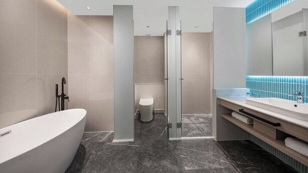 A modern bathroom with a freestanding bathtub, a glass-enclosed shower, and a vanity with a mirror. - Holiday Inn Express Taizhou Toumen Port by IHG (Taizhou)