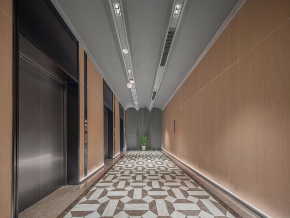 A hallway with a patterned floor, elevators, and a potted plant. - Holiday Inn Express Taizhou Toumen Port by IHG (Taizhou)