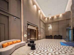 A spacious lobby with a modern design, featuring a large seating area with a sofa and ottoman, a patterned floor, and a ceiling with a unique light fixture. - Holiday Inn Express Taizhou Toumen Port by IHG (Taizhou)