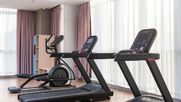 Ein modernes Fitnessstudio mit zwei Laufbändern, einem Ergometer und einer Gewichtshalterung.