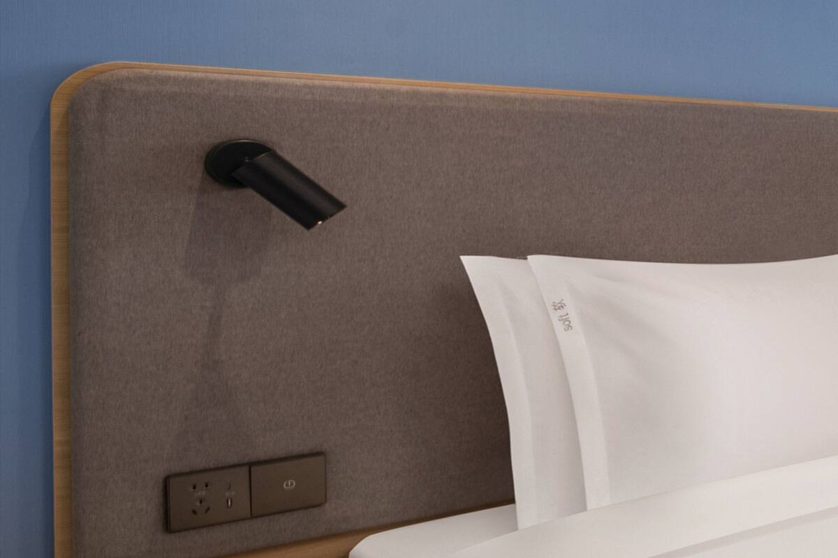 A bed with a headboard, a power outlet, and a switch.