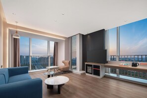 A modern living room with a large TV, a sofa, a coffee table, and a view of the cityscape through large windows. - Holiday Inn Express Taizhou Toumen Port by IHG (Taizhou)
