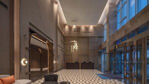 A spacious lobby with a geometric patterned floor, a modern chandelier, and a reception desk. - Holiday Inn Express Taizhou Toumen Port by IHG (Taizhou)