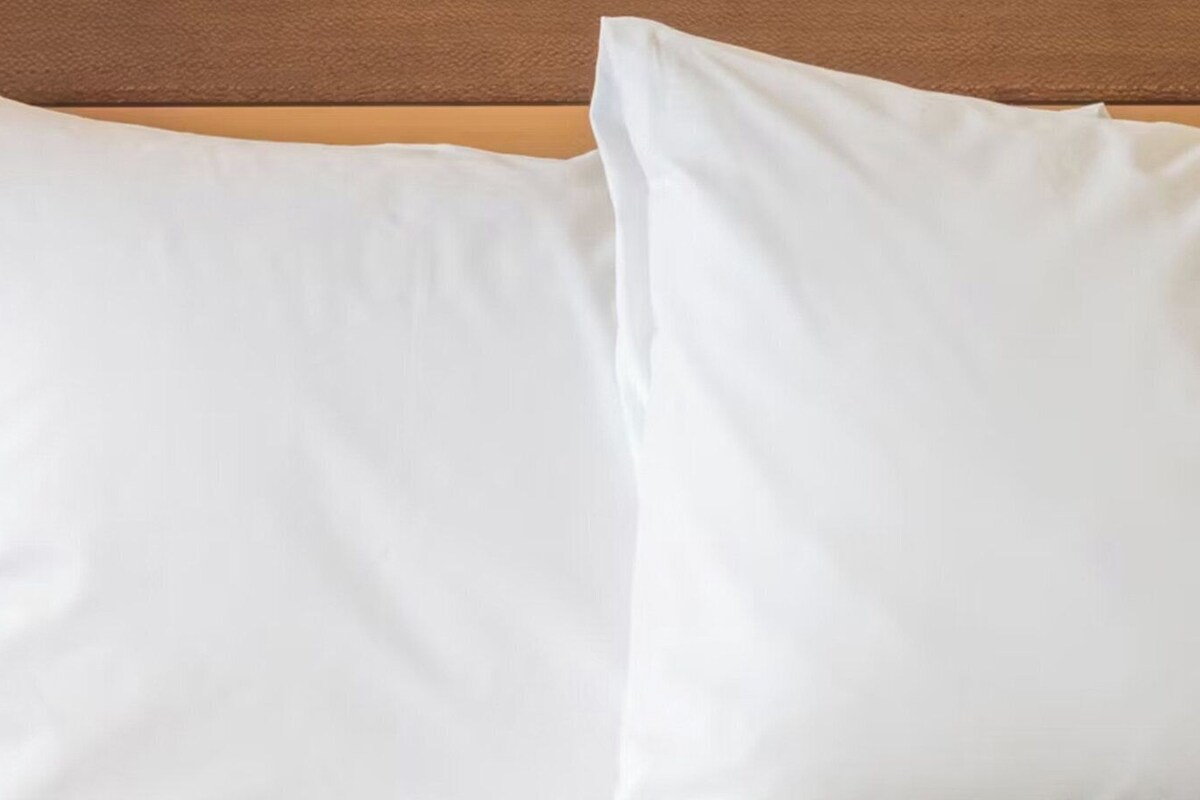 Two white pillows against a wooden headboard.