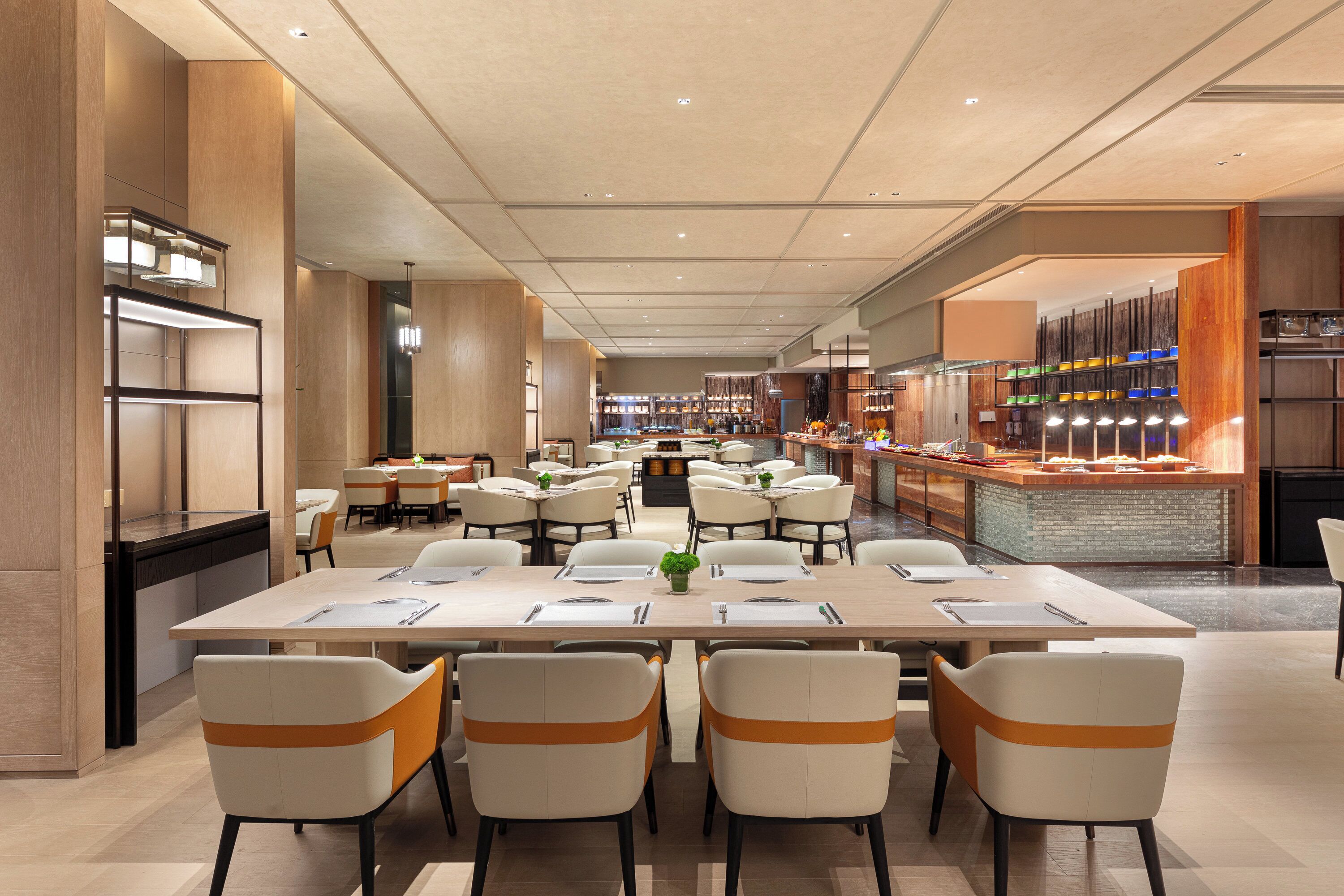 A spacious dining area with multiple tables and chairs, a central island with a bar, and a kitchen area visible in the background.