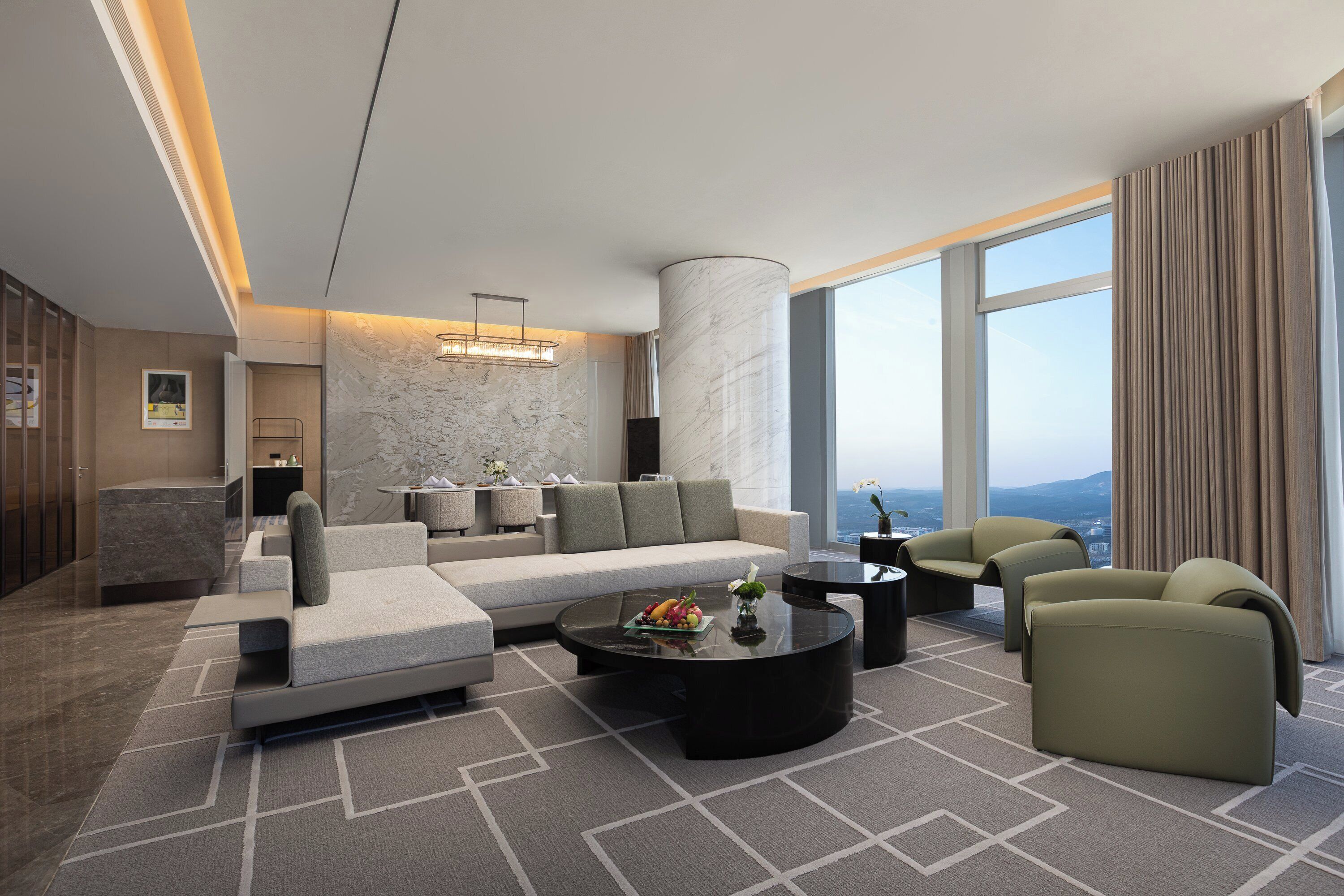 Een moderne woonkamer met een bank, fauteuils, een salontafel en uitzicht op de stad.