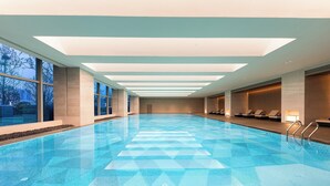 A large indoor swimming pool with clear blue water, a geometric pattern on the floor, and a modern ceiling design. - Crowne Plaza Jingmen by IHG (Jingmen)
