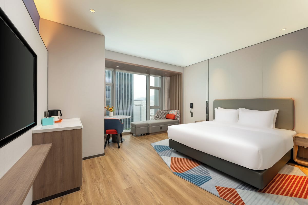Una habitación de hotel moderna con una cama grande, un escritorio y un área de descanso.