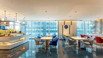Un comedor moderno con paredes de vidrio, un bufé y muebles contemporáneos.