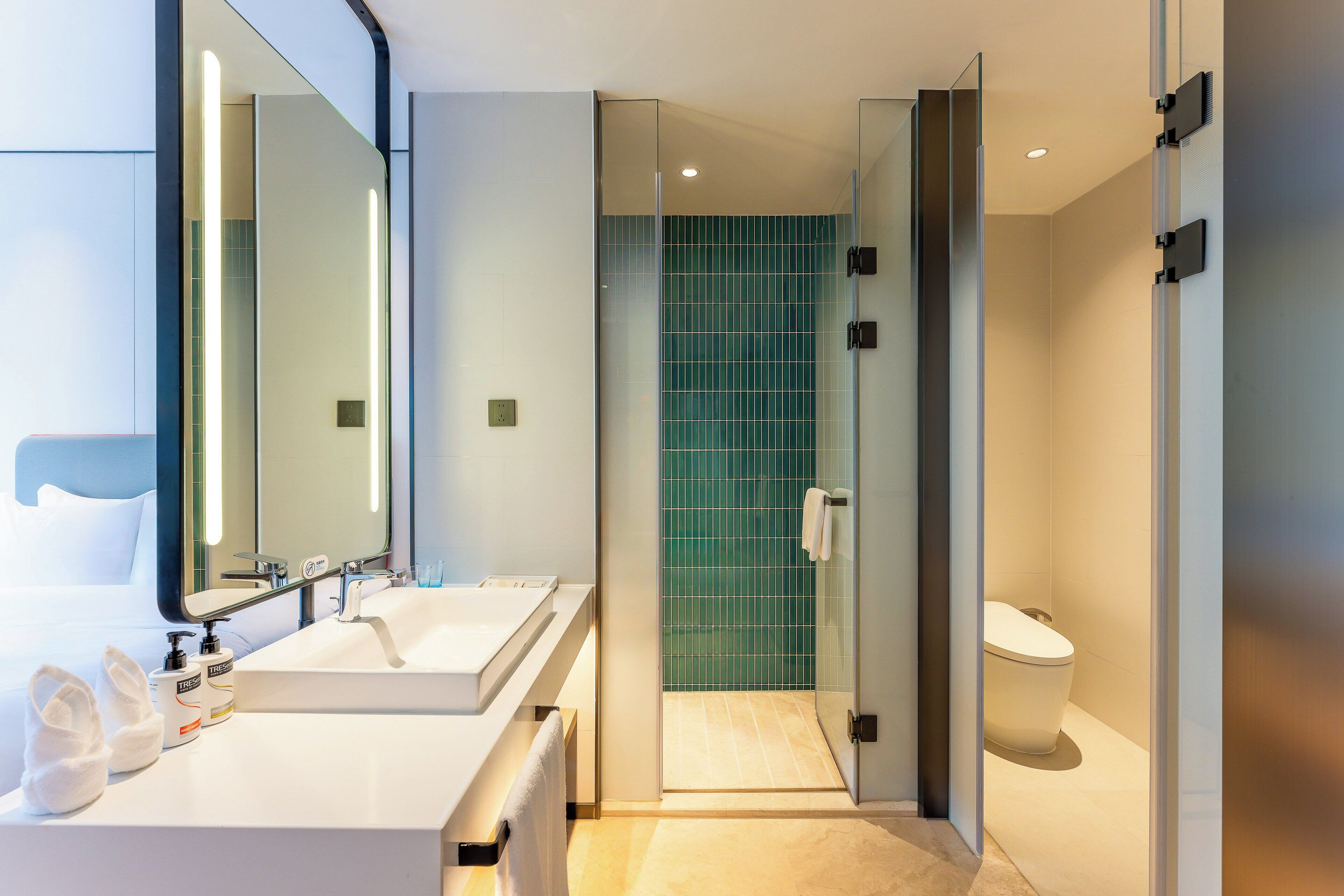 A modern bathroom with two sinks, a large mirror, and a glass shower enclosure.