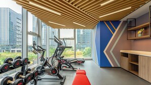 Una palestra moderna con attrezzature per esercizi, ampie finestre e vista sugli edifici.