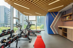 A modern gym with exercise equipment, large windows, and a view of buildings. - Holiday Inn Express Shenzhen Guangming by IHG (Shenzhen)
