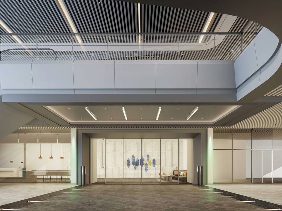 A spacious lobby with a high ceiling, modern lighting, and a seating area with tables and chairs.