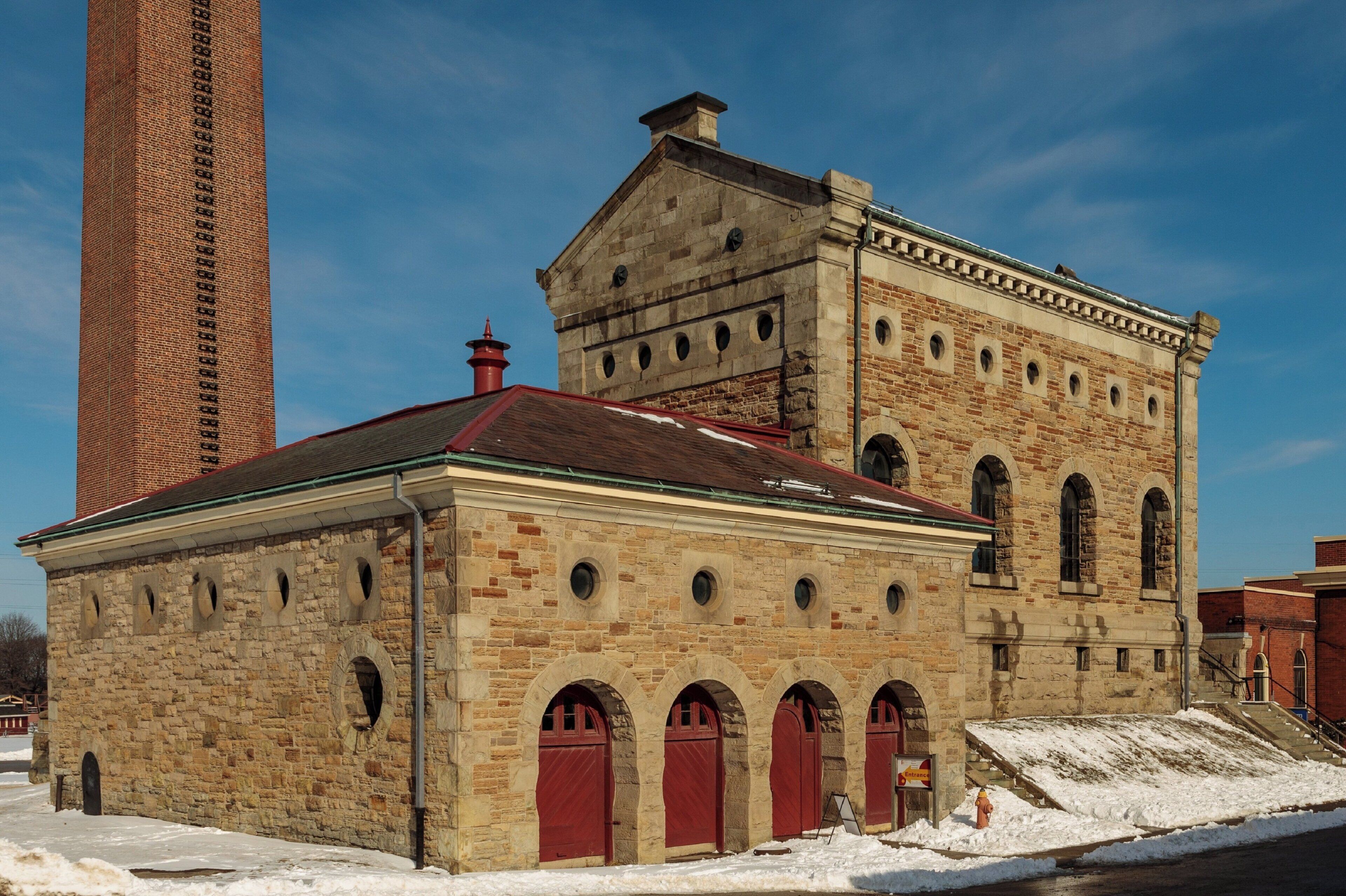 A historic building with a brick tower, arched windows, and red doors.