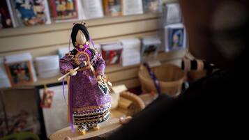 Una persona sosteniendo una muñeca vestida con un traje morado con detalles dorados.