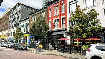 A street with parked cars, a red brick building with a sign, and a sidewalk with a planter.