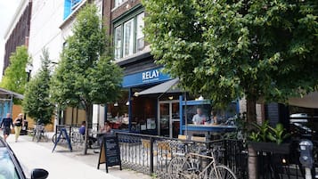 Calle con terraza al aire libre frente a una torrefactora de café llamada 'RELAY', bicicletas estacionadas y acera.
