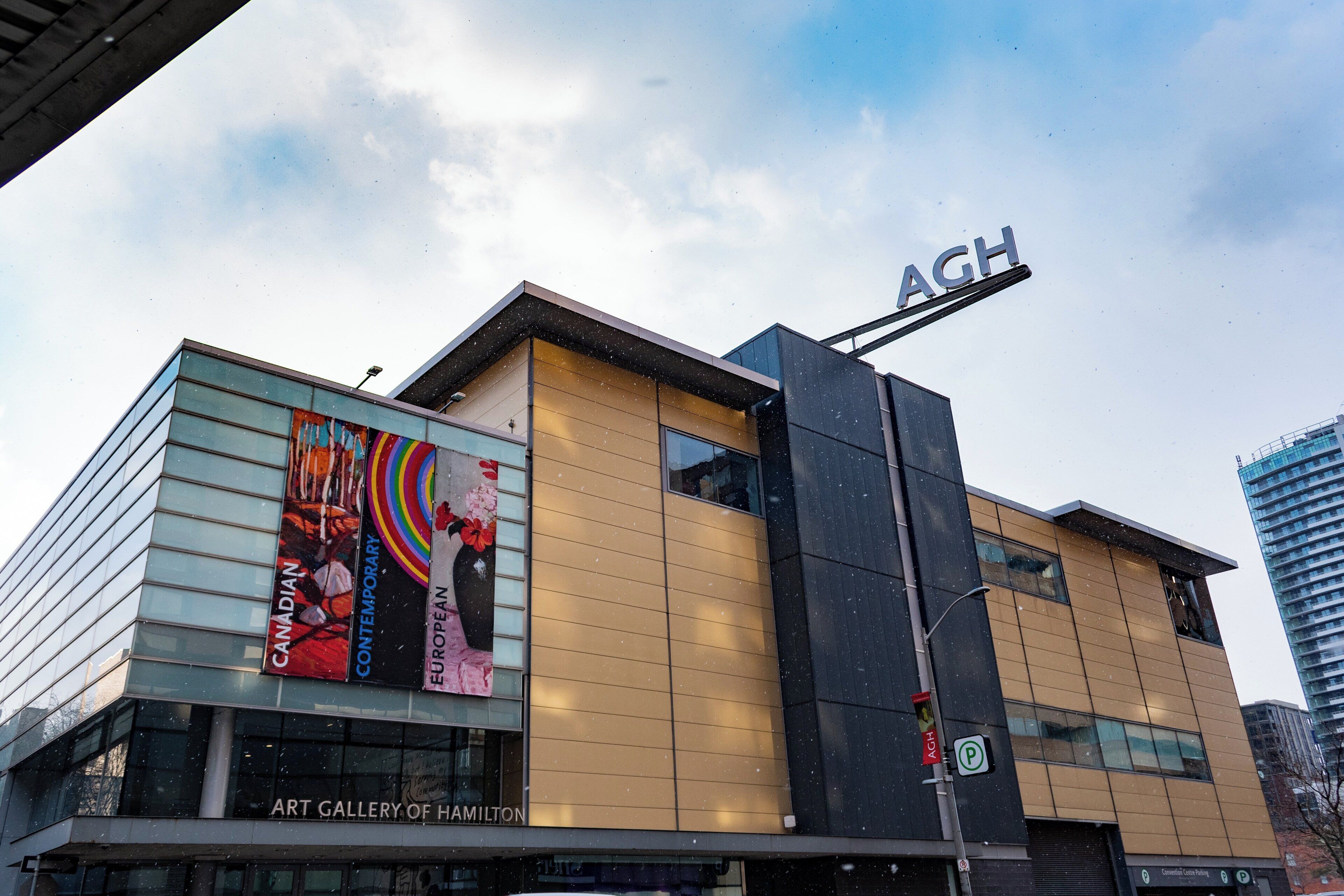 A modern building with a prominent 'AHG' sign, a glass facade, and an 'Art Gallery of Hamilton' sign.