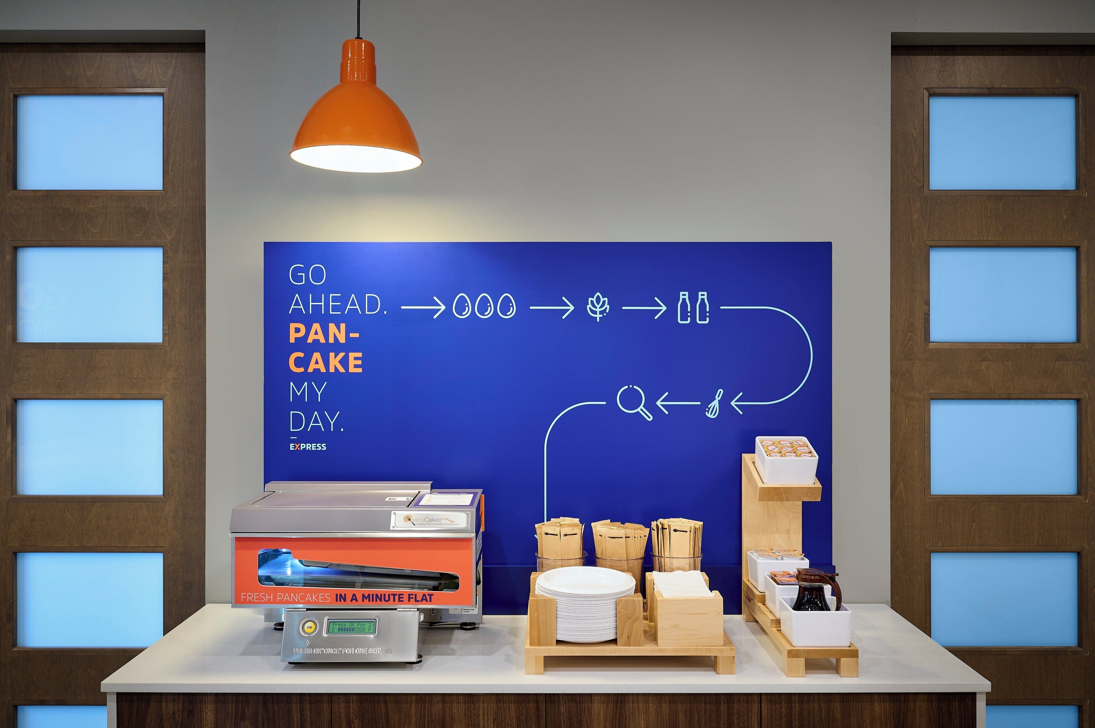 A breakfast station with a sign, a coffee machine, and breakfast items.