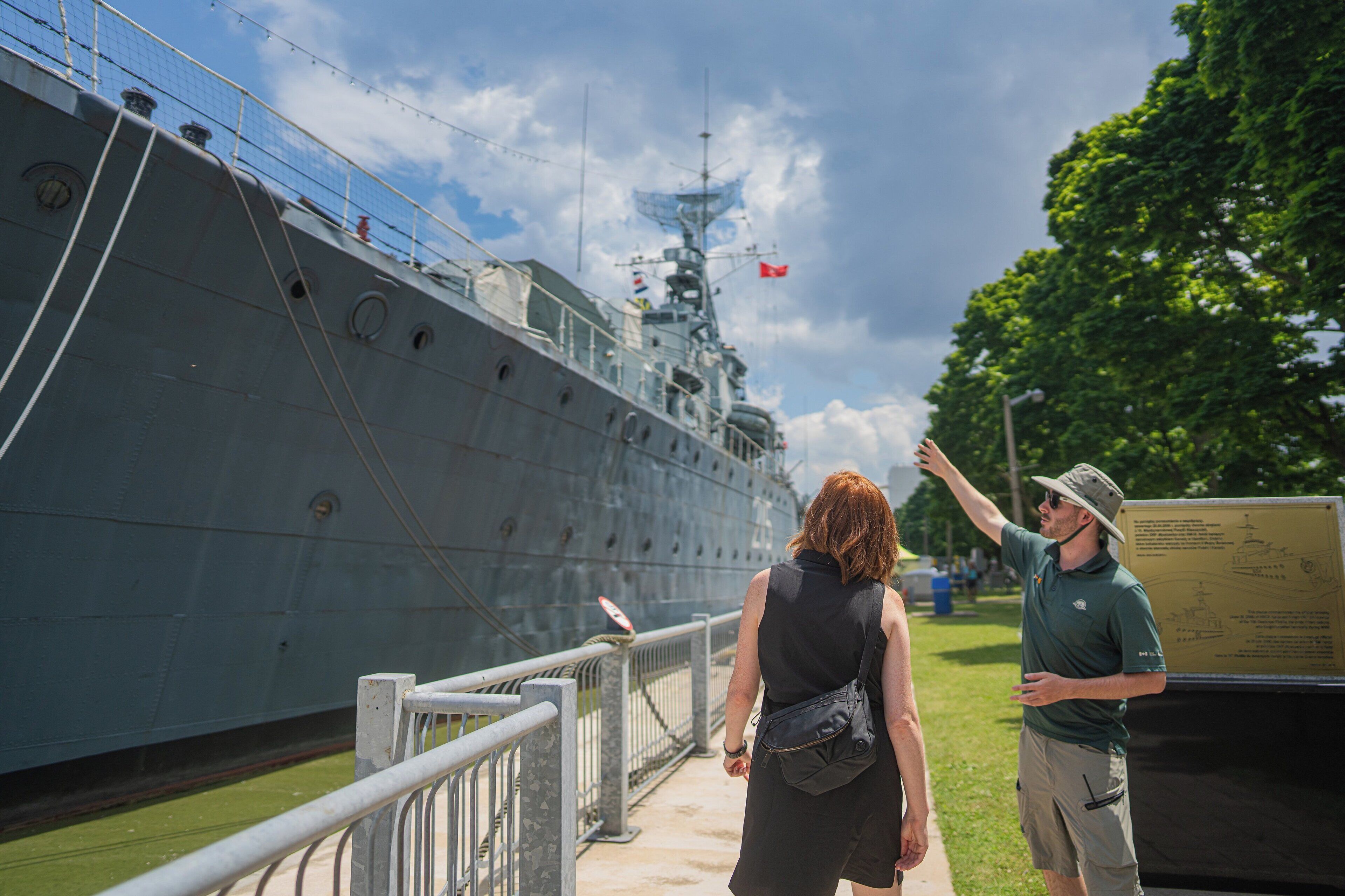 A large ship docked at a port with a person pointing towards it.